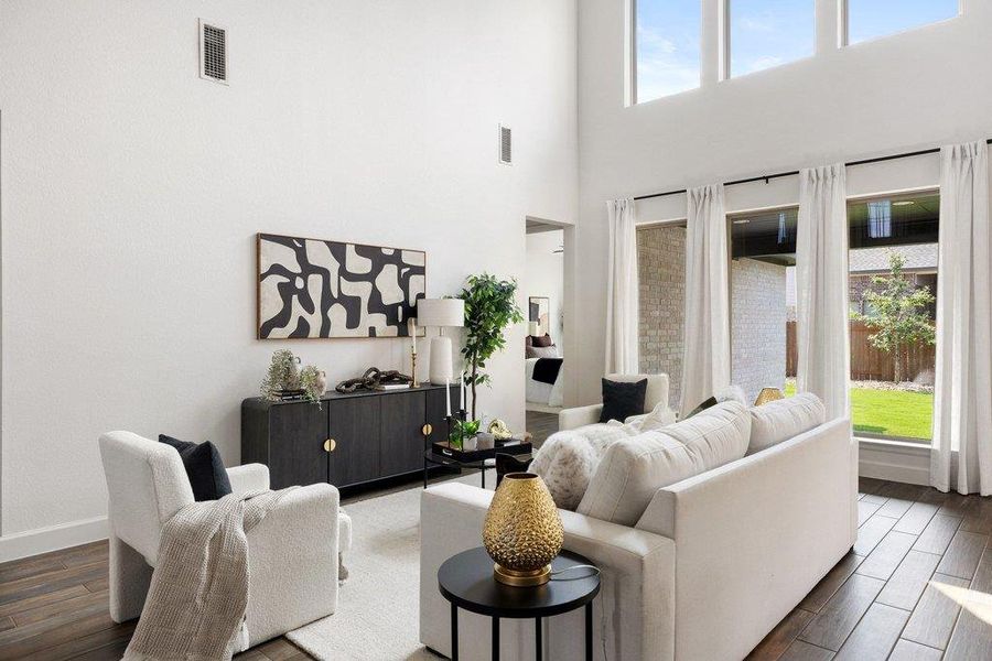 Natural light floods this living room, featuring high ceilings and rich wood flooring.
