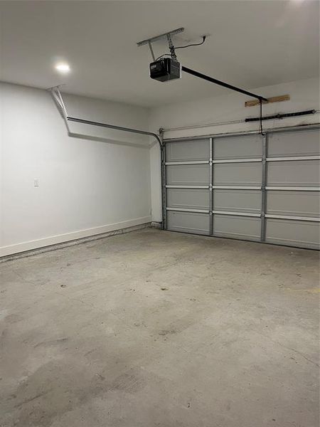 Spacious garage featuring a sectional overhead door, automatic opener, concrete flooring, and recessed ceiling lighting
