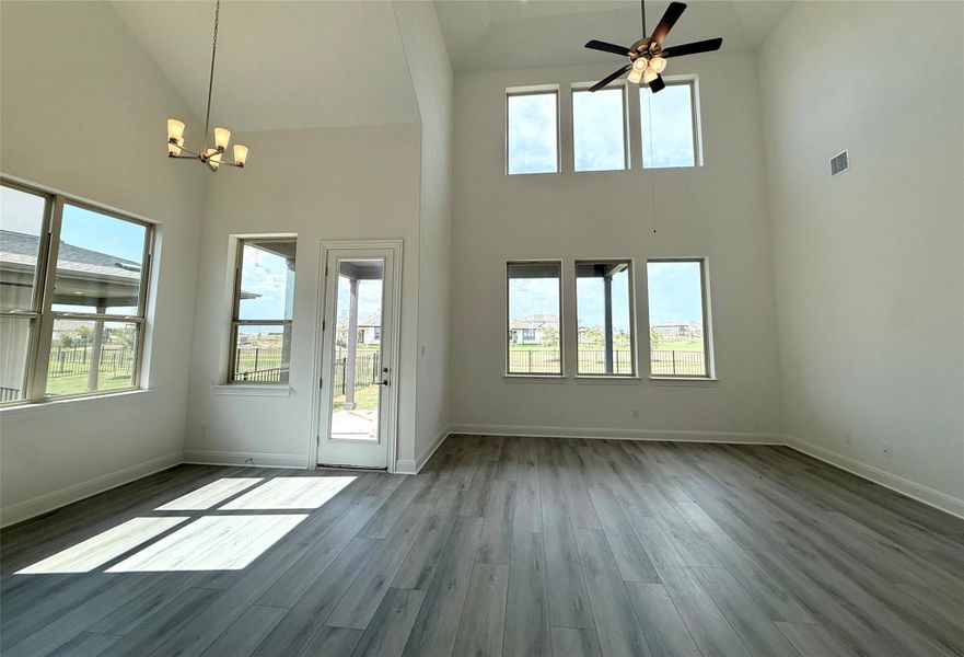 Unfurnished living room with wood finished floors, a chandelier, high vaulted ceiling, and ceiling fan Unfurnished living room with wood finished floors, a chandelier, high vaulted ceiling, and ceiling fan