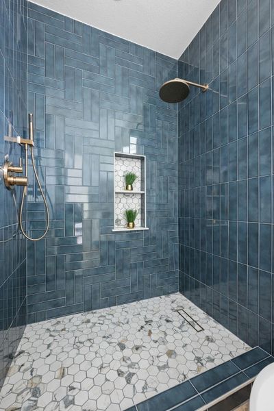 Walk-in shower with blue subway tile walls in a herringbone pattern