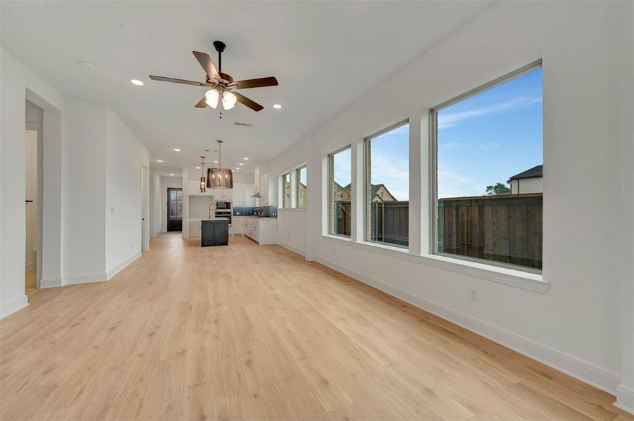 Expansive room featuring light wood-finish flooring, recessed lighting, and a modern ceiling fan