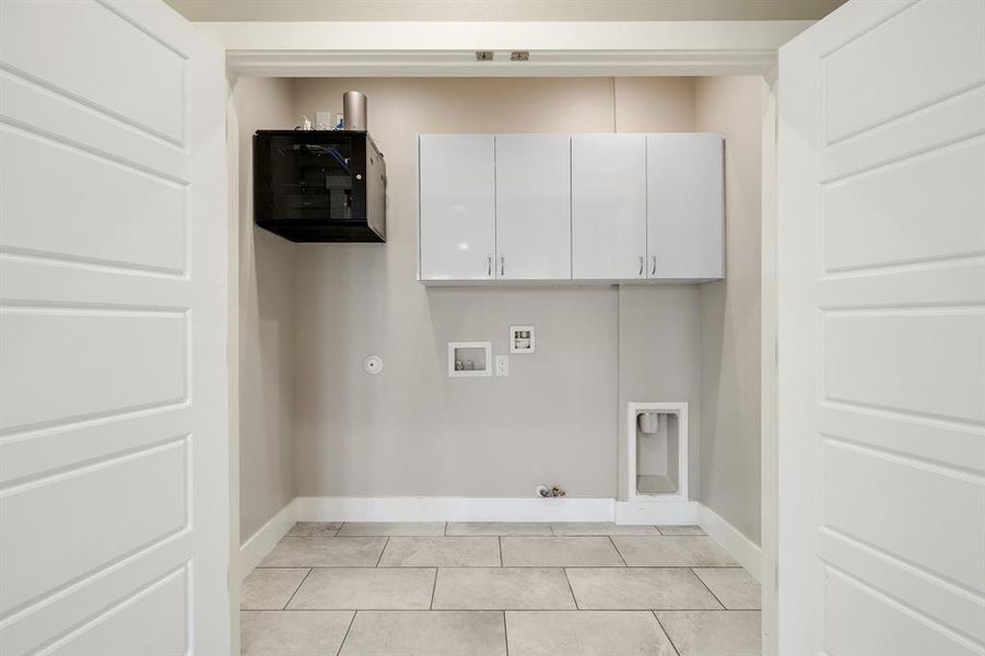 Washroom with washer hookup, gas dryer hookup, cabinets, and light tile patterned floors