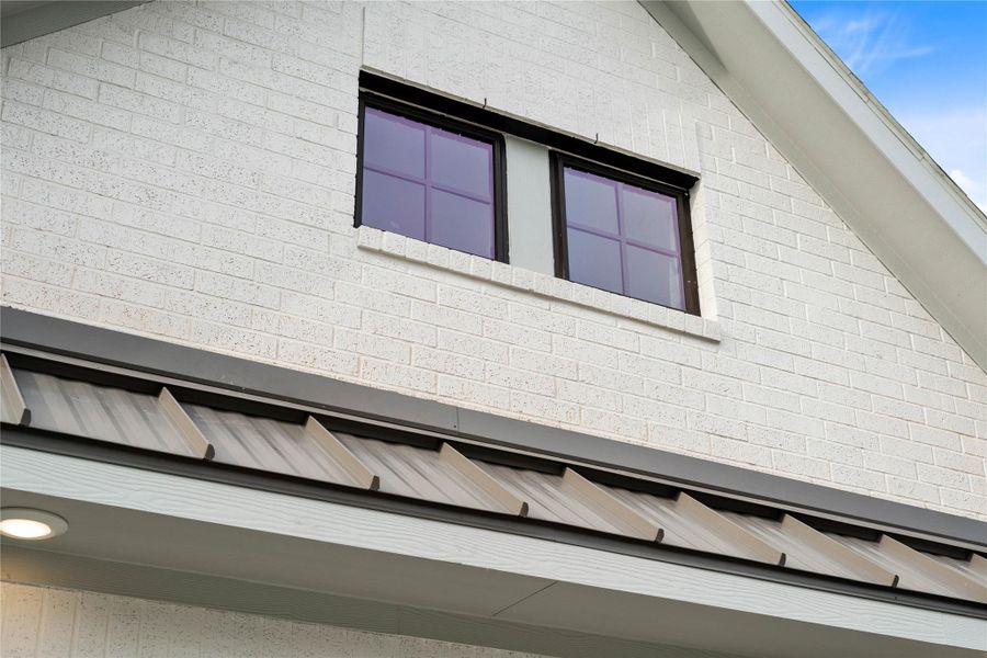 A prominent dormer window with a dark black frame and grid panes is set within the brick facade, adding architectural interest and natural light to the interior space.