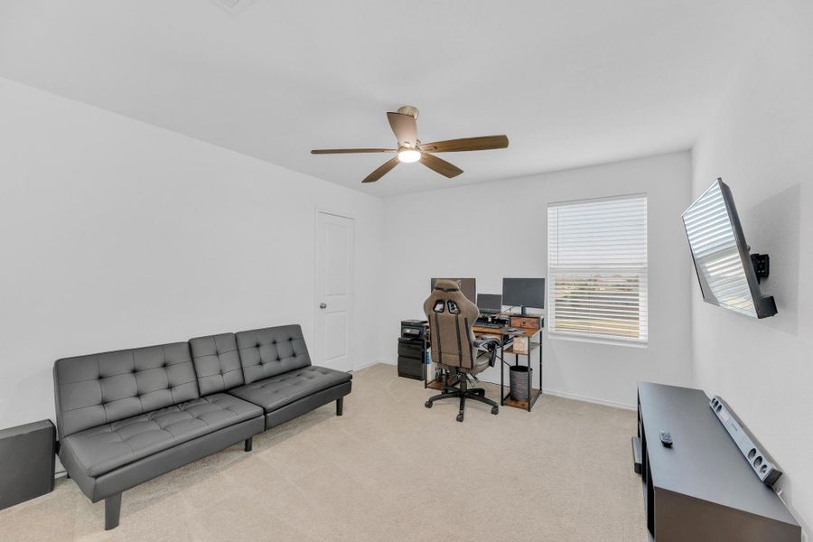 Office space featuring light carpet, baseboards, and a ceiling fan