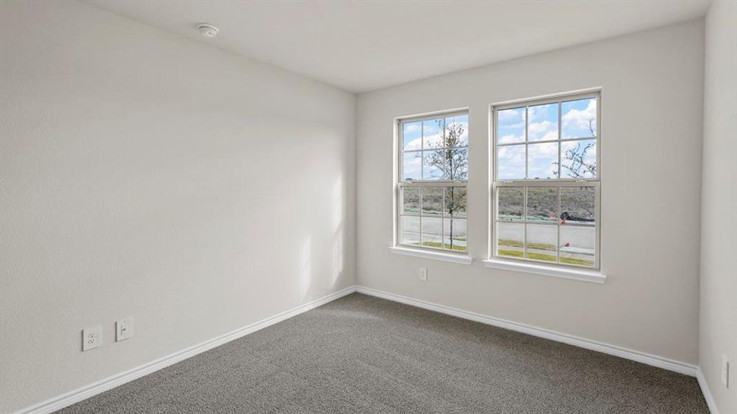 Room featuring twin double-hung windows with grid patterns, light gray carpeting, neutral wall paint, and white trim Room featuring twin double-hung windows with grid patterns, light gray carpeting, neutral wall paint, and white trim