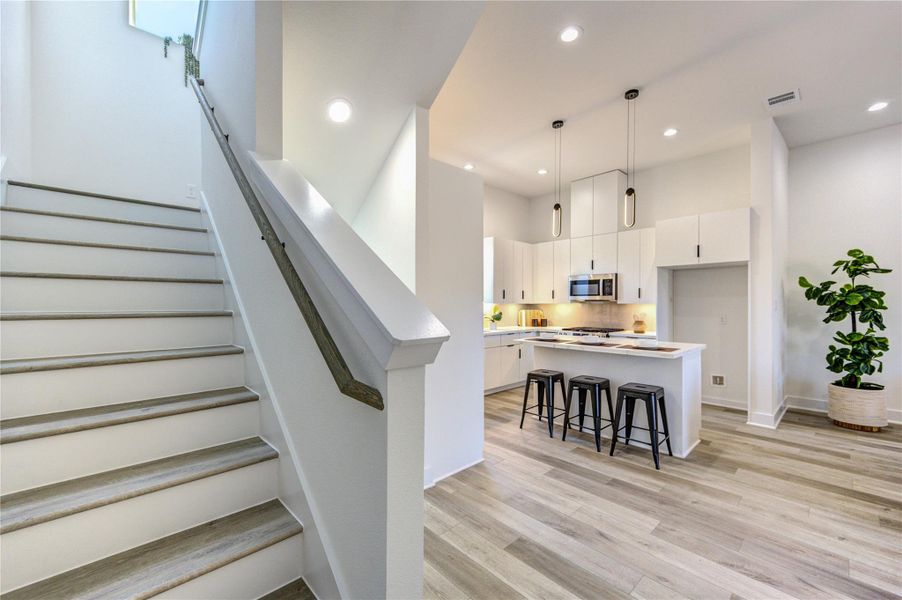 Modern kitchen with sleek white cabinetry, an island with pendant lighting.