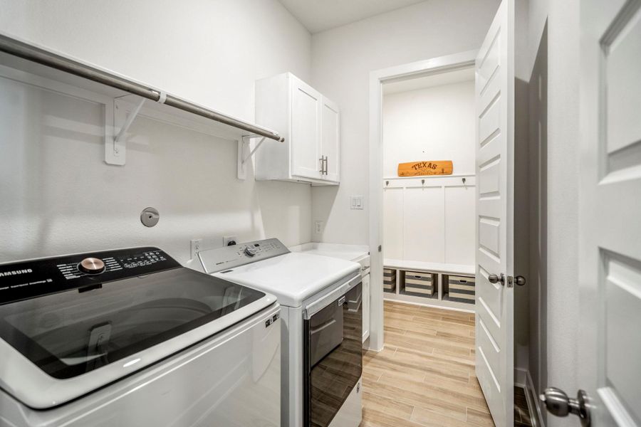 The laundry room includes additional storage & extends into a mudroom area with a bench, hooks, and storage bins, providing functionality and organization.