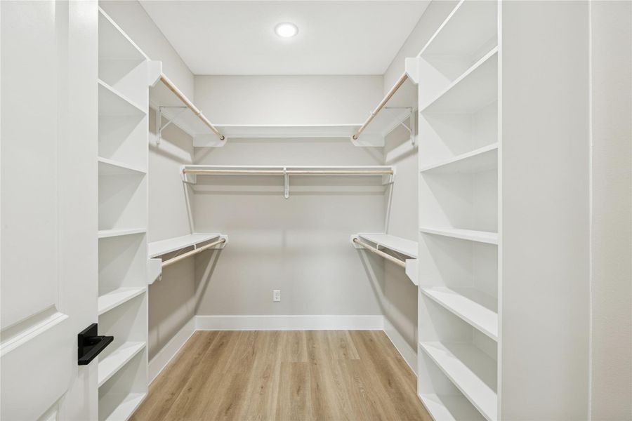 Spacious primary bedroom closet with ample shelving and hanging space.