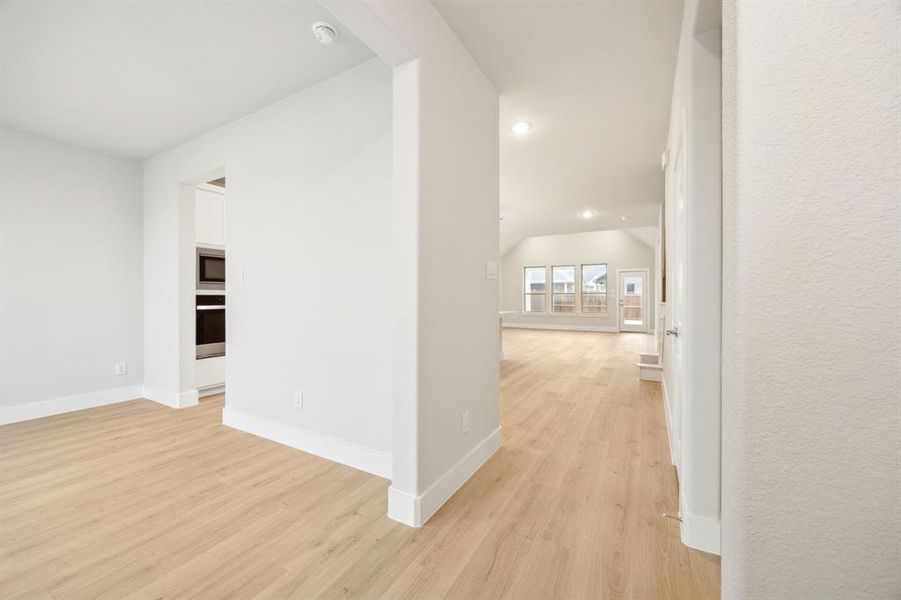 Hallway featuring lofted ceiling and light wood-type flooring