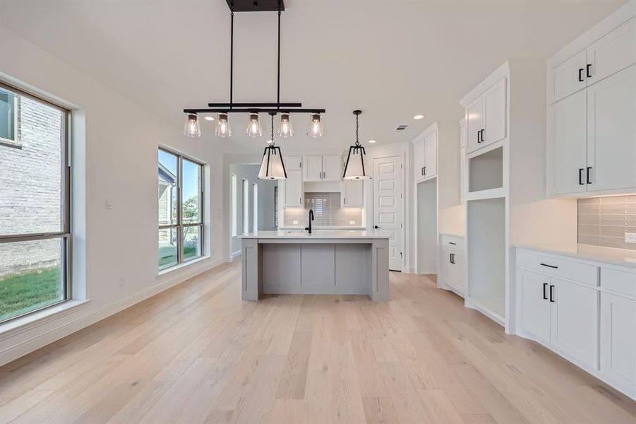 Kitchen featuring light hardwood / wood-style floors, decorative backsplash, and white cabinets