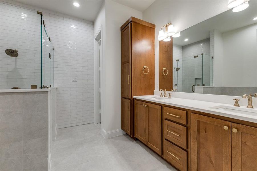 Full bathroom featuring a tile shower, double vanity, recessed lighting, and tile patterned floors