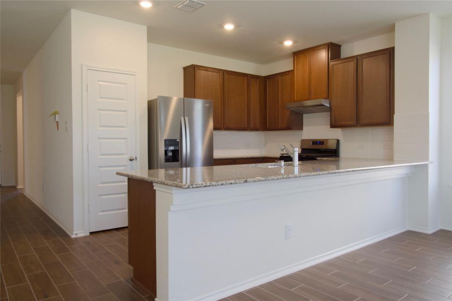A well-lit kitchen with granite countertops and rich wood cabinetry, offering modern culinary convenience.