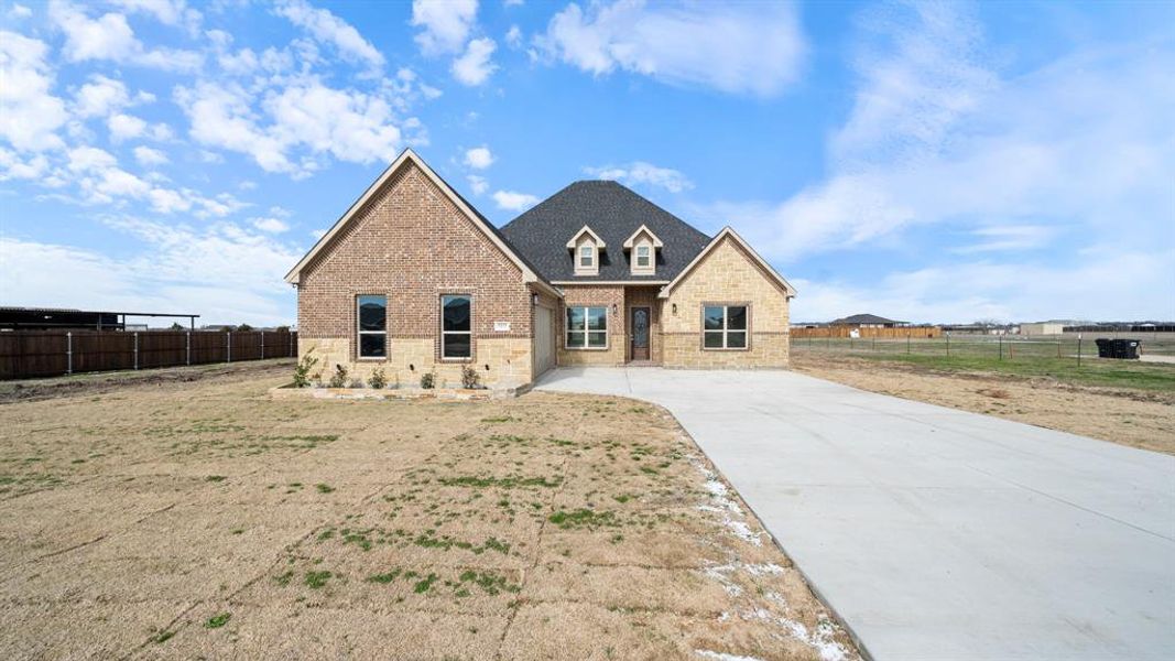 View of front of house featuring stone siding, brick siding, and fence