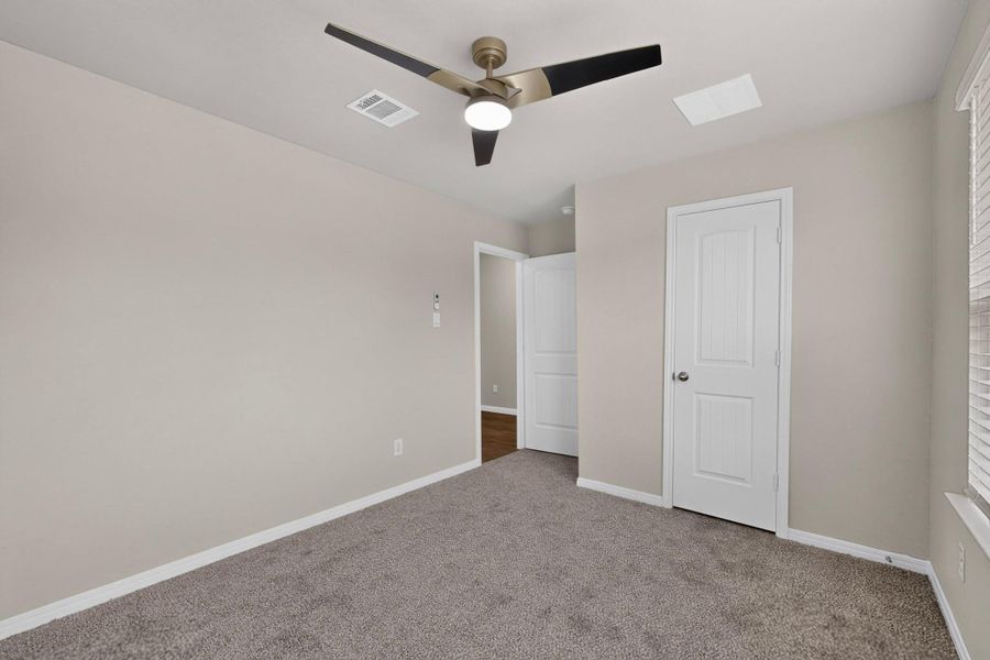 Soft carpeting underfoot and neutral-toned walls define this versatile secondary bedroom space.