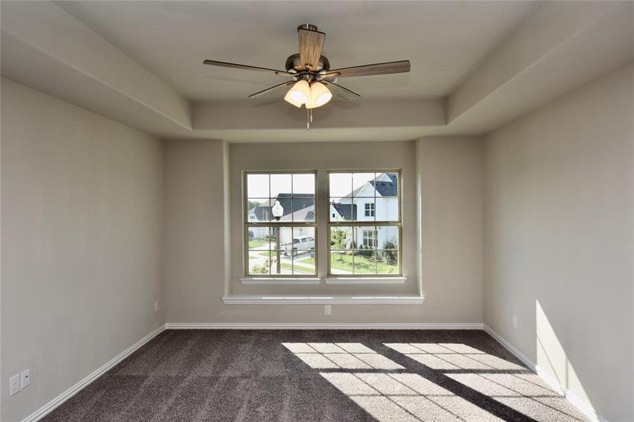 Bedroom featuring neutral carpet, a raised ceiling, and ceiling fan