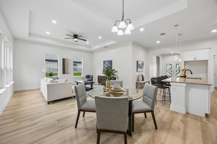 Open-concept living space featuring recessed lighting, a tray ceiling and a kitchen island