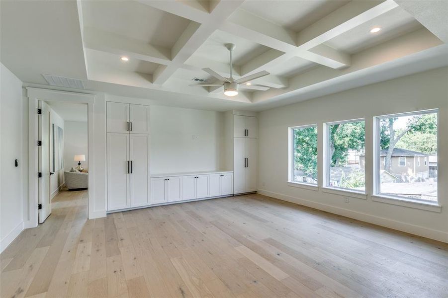 Unfurnished bedroom featuring multiple windows, light hardwood / wood-style floors, and coffered ceiling