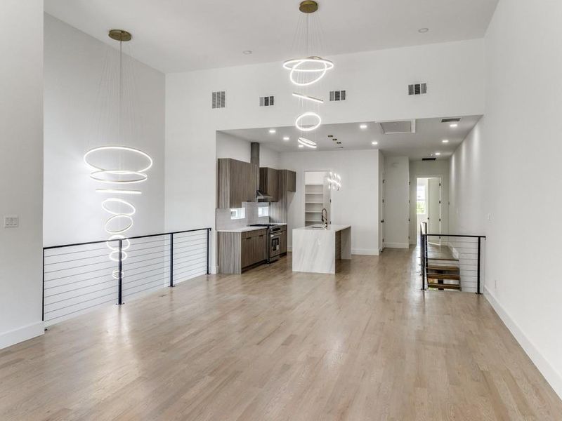 Unfurnished living room with a high ceiling, light wood-style floors, and a chandelier