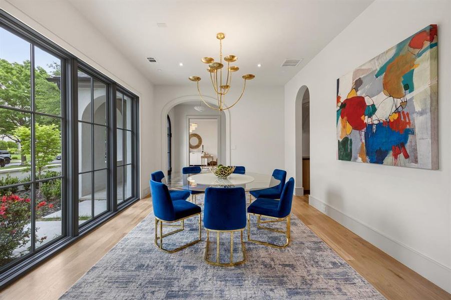 Spacious room featuring wood-finish flooring, a contemporary gold-tone chandelier, and large paneled windows Spacious room featuring wood-finish flooring, a contemporary gold-tone chandelier, and large paneled windows