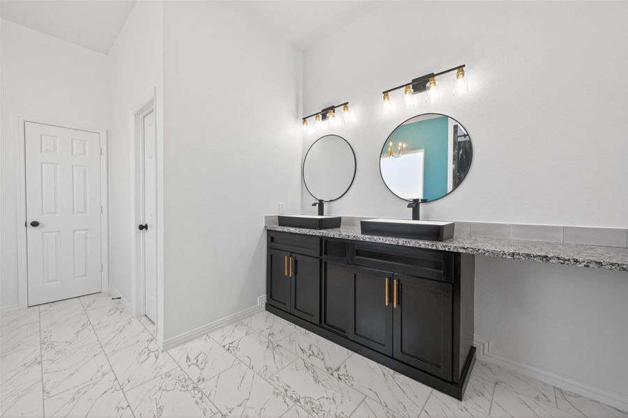 Elegant primary bathroom with dual sinks, custom cabinetry, a freestanding soaking tub, and walk-in shower.