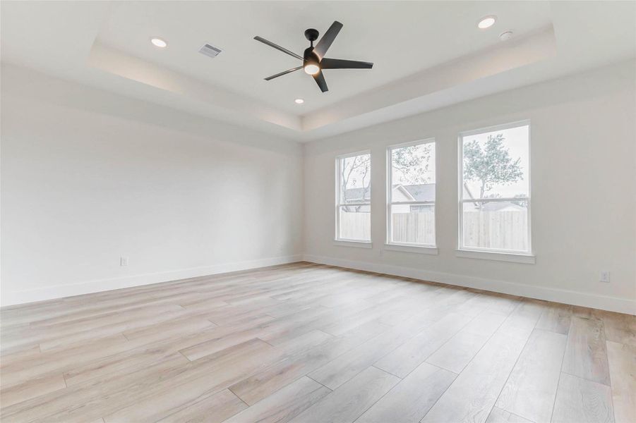 Elegant retreat with 9 ft ceilings and a 10 ft tray, modern remote fan, and expansive windows overlooking the backyard.A peaceful, light-filled space designed for comfort and relaxation.