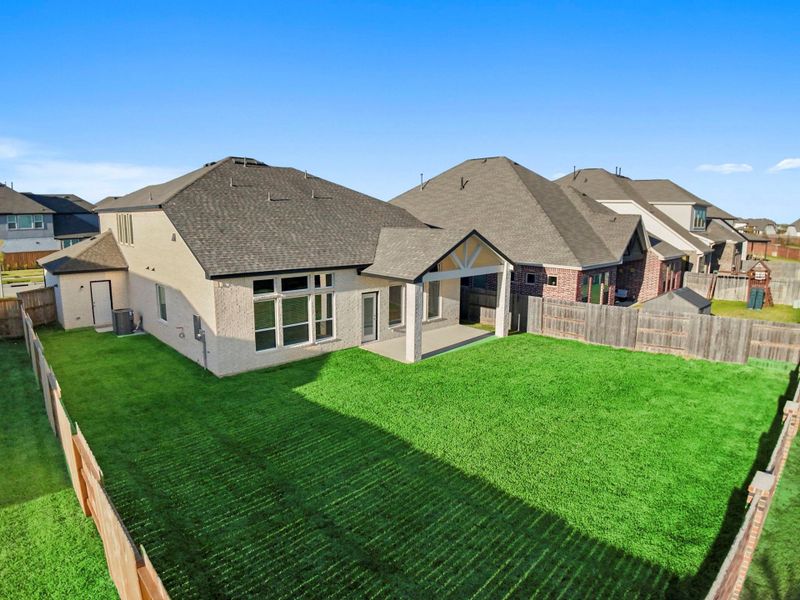 The rear view of the home showcases the all-brick exterior, combining durability and timeless style. The covered patio seamlessly extends the living space outdoors, ideal for relaxing or entertaining.