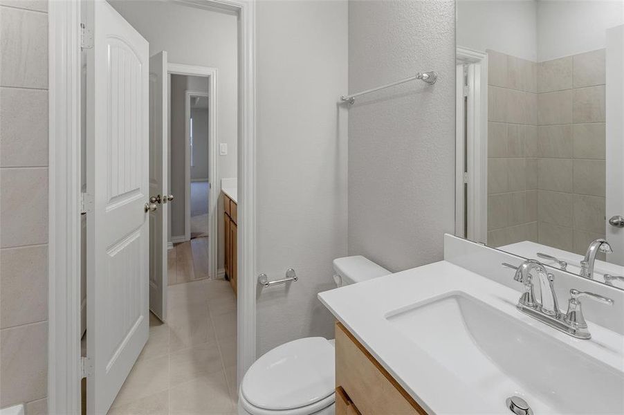 Bathroom featuring a light wood-finish vanity with a white countertop and integrated sink, chrome faucet, and expansive wall mirror