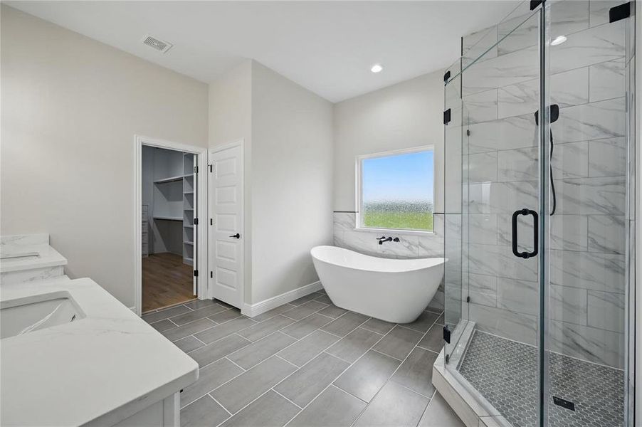Full bath with a walk in closet, a shower stall, a soaking tub, double vanity, and recessed lighting Full bath with a walk in closet, a shower stall, a soaking tub, double vanity, and recessed lighting