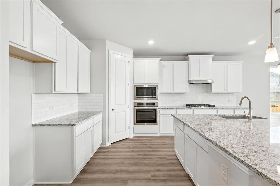 Kitchen featuring stainless steel appliances, under cabinet range hood, light wood finished floors, backsplash, and recessed lighting Kitchen featuring stainless steel appliances, under cabinet range hood, light wood finished floors, backsplash, and recessed lighting