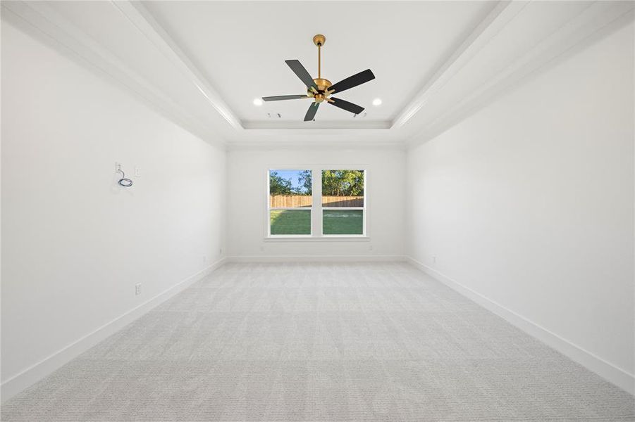 Spacious interior room featuring a tray ceiling with a ceiling fan, recessed lighting, and light-colored carpeting