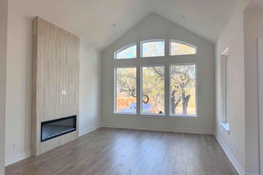 Unfurnished living room with dark wood-style floors and a large fireplace