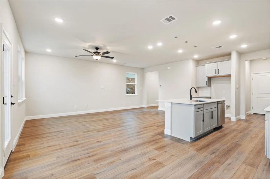 Kitchen featuring sink, a center island with sink, light hardwood / wood-style flooring, ceiling fan, and backsplash