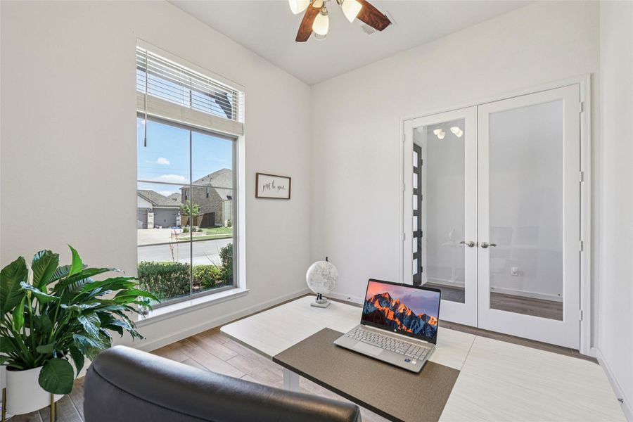 Bright room featuring a large window, french doors, and a ceiling fan