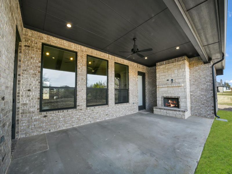 View of patio with an outdoor stone fireplace and ceiling fan