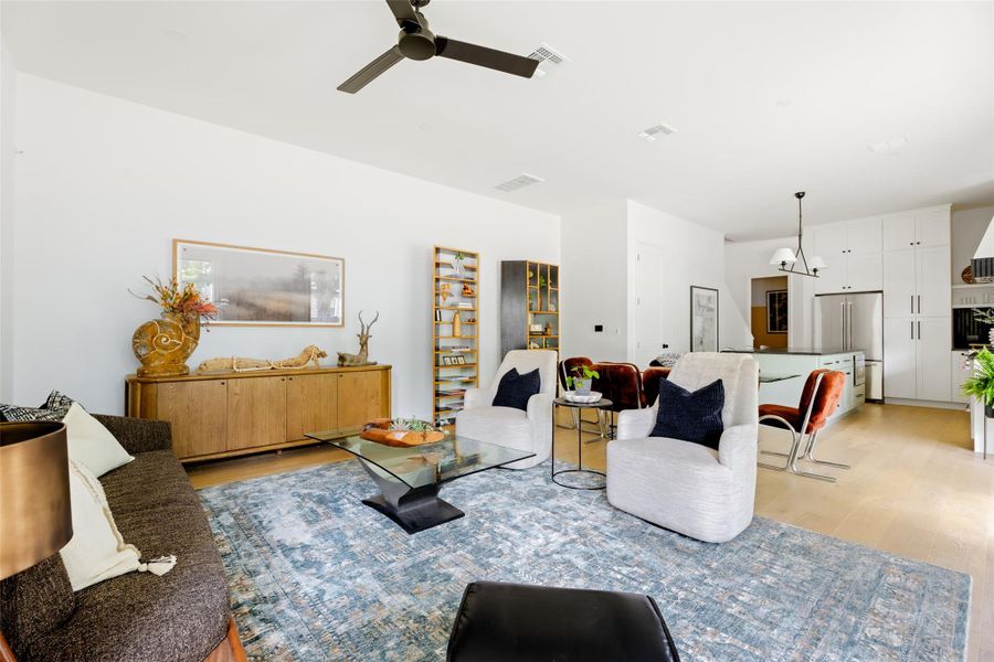 Living room featuring light wood-style floors, ceiling fan, and visible vents