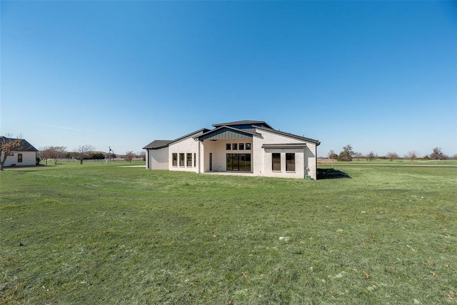 Rear view of property with a lawn and a patio area
