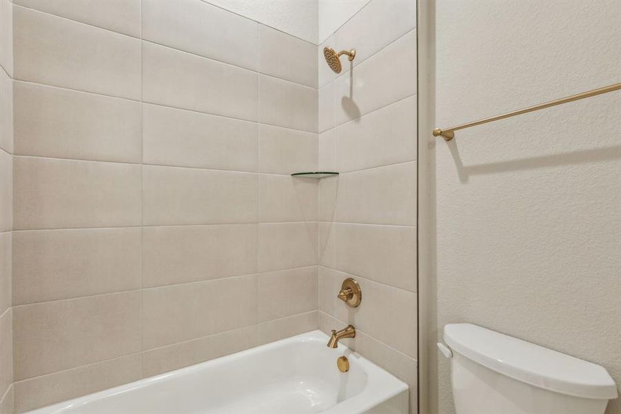 Bathroom with toilet and tiled shower / bath combo