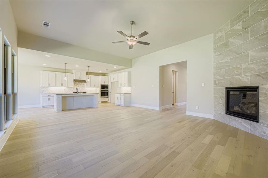 Unfurnished living room with a fireplace, light wood-style floors, a ceiling fan, and recessed lighting