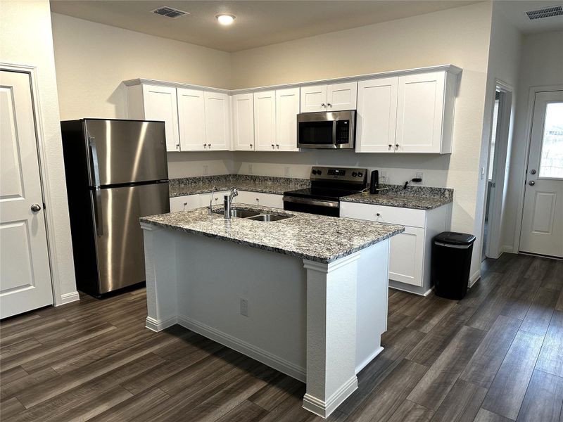 Kitchen featuring dark wood finished floors, appliances with stainless steel finishes, a sink, and refrigerator conveys with property.