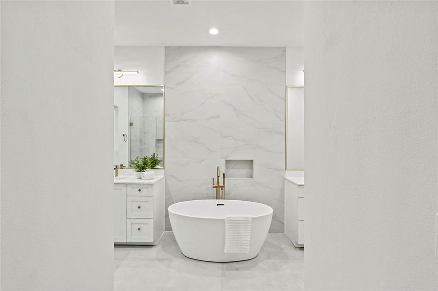 Bathroom featuring vanity, tile walls, a washtub, and tile patterned floors