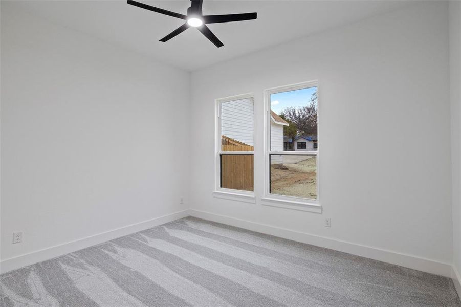 Carpeted spare room with baseboards and a ceiling fan