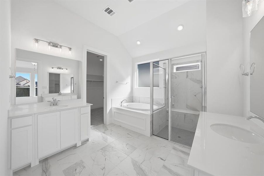 Full bath with a bath, two vanities, vaulted ceiling, light marble finish flooring, and a marble finish shower Full bath with a bath, two vanities, vaulted ceiling, light marble finish flooring, and a marble finish shower