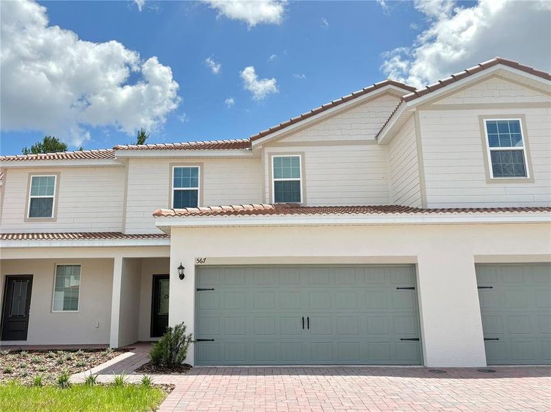 Front exterior of a new home in Noah Estates at Tuscany Preserve, Poinciana, FL, highlighting curb appeal (Image 1).