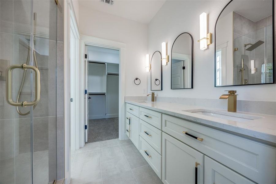 Bathroom with vanity, a shower with shower door, and tile patterned flooring