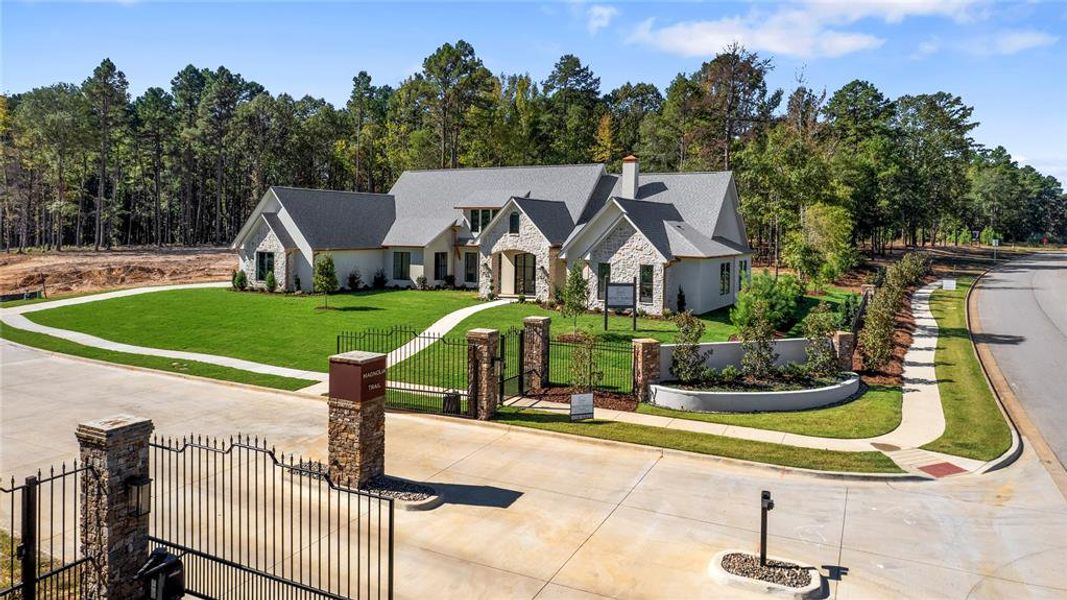 View of front of house with a gate, a fenced front yard, stone siding, a chimney, and driveway