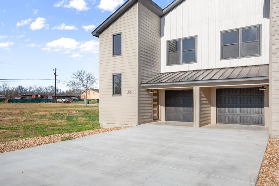 View of property exterior with driveway, an attached garage, board and batten siding, and a standing seam roof