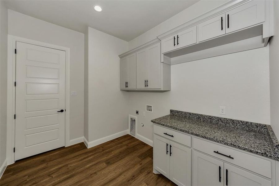 Washroom featuring hookup for an electric dryer, hookup for a washing machine, dark wood-type flooring, cabinet space, and hookup for a gas dryer