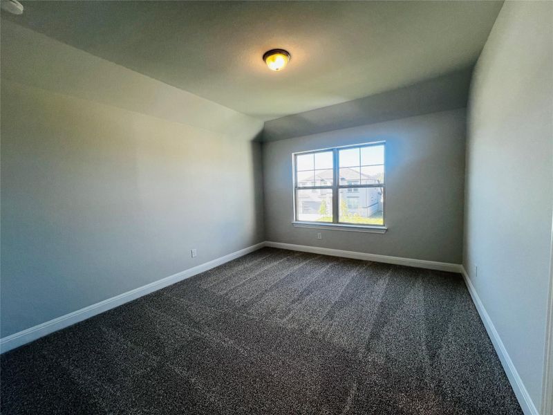 Empty room featuring dark carpet and vaulted ceiling