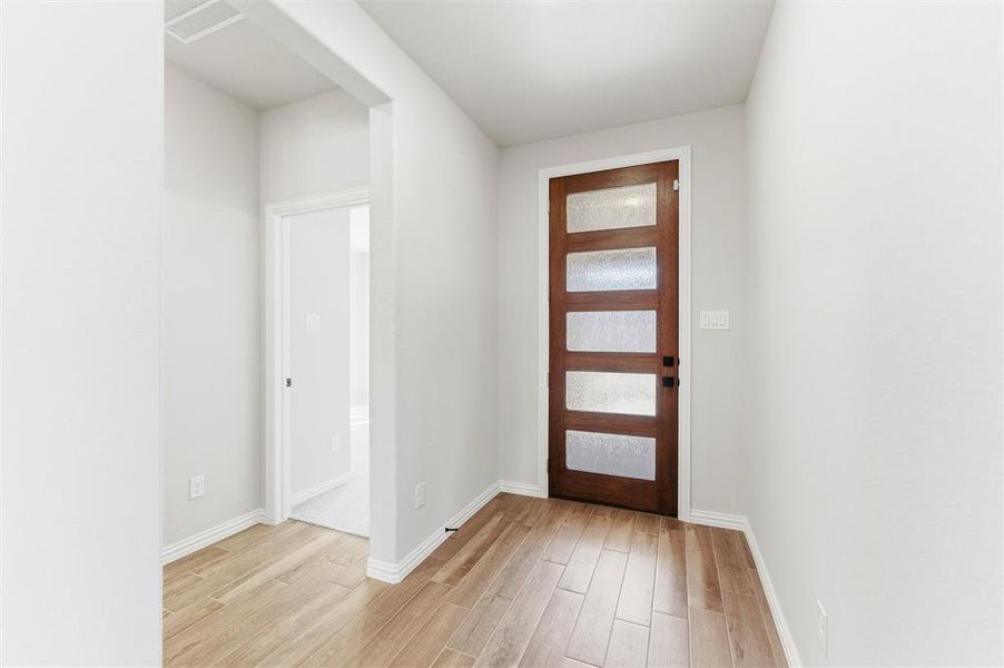 Foyer with light wood-style floors and baseboards