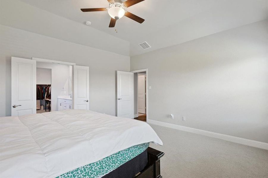 Carpeted bedroom with ceiling fan, a closet, vaulted ceiling, and a spacious closet